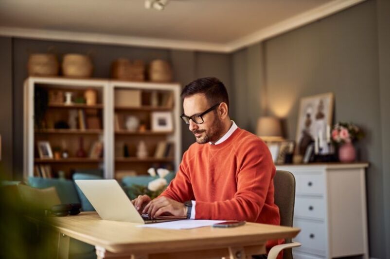 A self employed man sits working at his desk on his laptop
