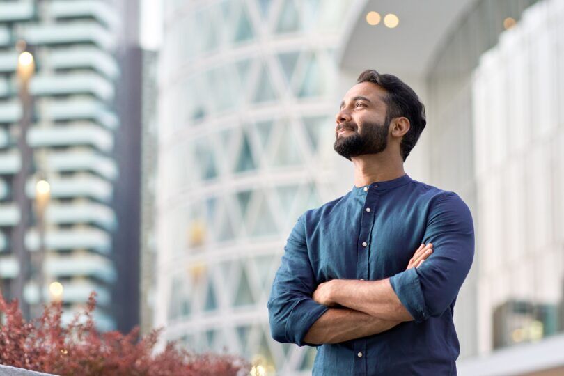 A business professional stands outside his job where he earns a £120K salary.