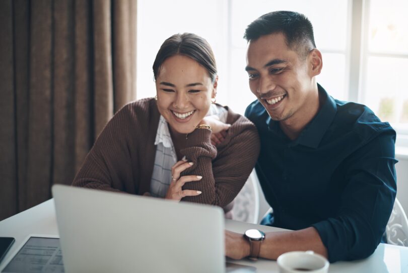 Couple improving their credit score on laptop before mortgage application in the UK